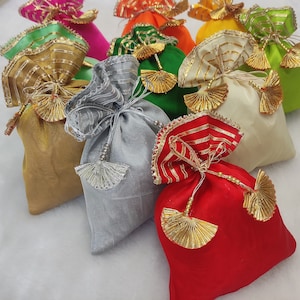 May include: Assortment of colorful fabric drawstring bags with gold trim and tassels. The bags are made of silk and have a variety of colors, including red, green, gold, silver, and white.