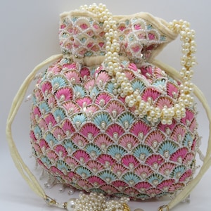 May include: A round, beaded bag in pink, light blue, and white, with a pearl beaded handle and drawstring closure. The bag is decorated with a fan-like pattern and small silver sequins. A tassel of pearls hangs from the bottom.