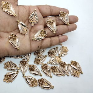 May include: A collection of gold and ivory floral embellishments with sequins. The embellishments are in the shape of a flower with a long stem.