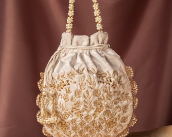 May include: A white velvet drawstring bag with gold embroidery and a pearl trim. The bag has a pearl handle and is perfect for special occasions.