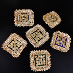 Peut inclure: Six décorations carrées avec des broderies dorées et argentées. Les décorations sont dans des tons de bleu, vert et noir.
