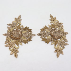 May include: Two gold embroidered floral appliques with a raised center and delicate leaf details.