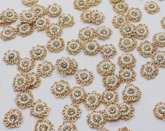 May include: A collection of gold and white beaded flower embellishments. The embellishments are made of small white beads and gold wire, and they have a delicate, feminine look.