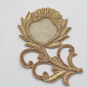 May include: Gold embroidered flower applique with a delicate mesh heart in the centre. The flower has a detailed stem and leaves.
