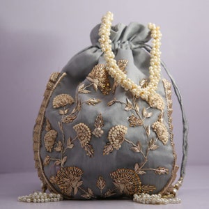 May include: A gray fabric drawstring bag with a pearl handle and gold embroidery of floral designs.