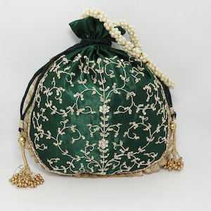 Può includere: Una borsa a cordoncino in satin verde con ricami dorati e una tracolla a catena di perle. La borsa ha un fiocco dorato.