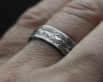 May include: A silver band ring with a textured surface.