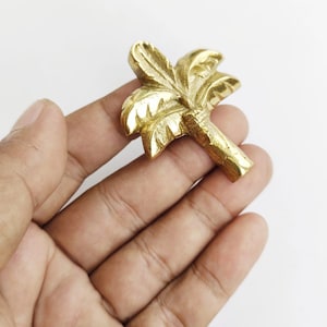 Puede incluir: Un pomo de puerta o armario en forma de palmera de color dorado.