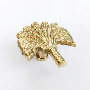 May include: A gold palm tree door knob with a detailed design. The knob is made of solid brass and has a smooth finish.