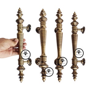 May include: Four antique brass door handles with a decorative, ornate design. Each handle features a fluted, cylindrical body with a pointed finial. The handles are mounted on a square plate.