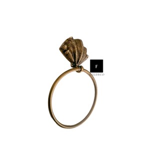 May include: A gold-toned towel ring with a seashell design. The ring is made of metal and has a smooth finish.