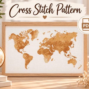 Könnte beinhalten: Ein Kreuzstichmuster mit einer Weltkarte in Brauntönen auf einem weißen Gitterhintergrund, präsentiert in einem hellen Holzrahmen. Der Text Cross Stitch Pattern steht über dem Rahmen und ein PDF-Symbol ist in der oberen Ecke zu sehen.
