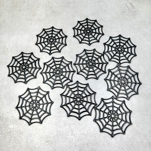 Puede incluir: Una colección de diez decoraciones de telarañas negras. Cada telaraña es circular con un patrón detallado de líneas radiales y círculos concéntricos, perfectas para Halloween o manualidades temáticas.