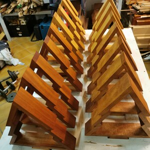May include: A set of 18 unfinished wooden triangular shelves, arranged in two rows of nine. The shelves are made of a light brown wood and have a natural, unpainted finish.