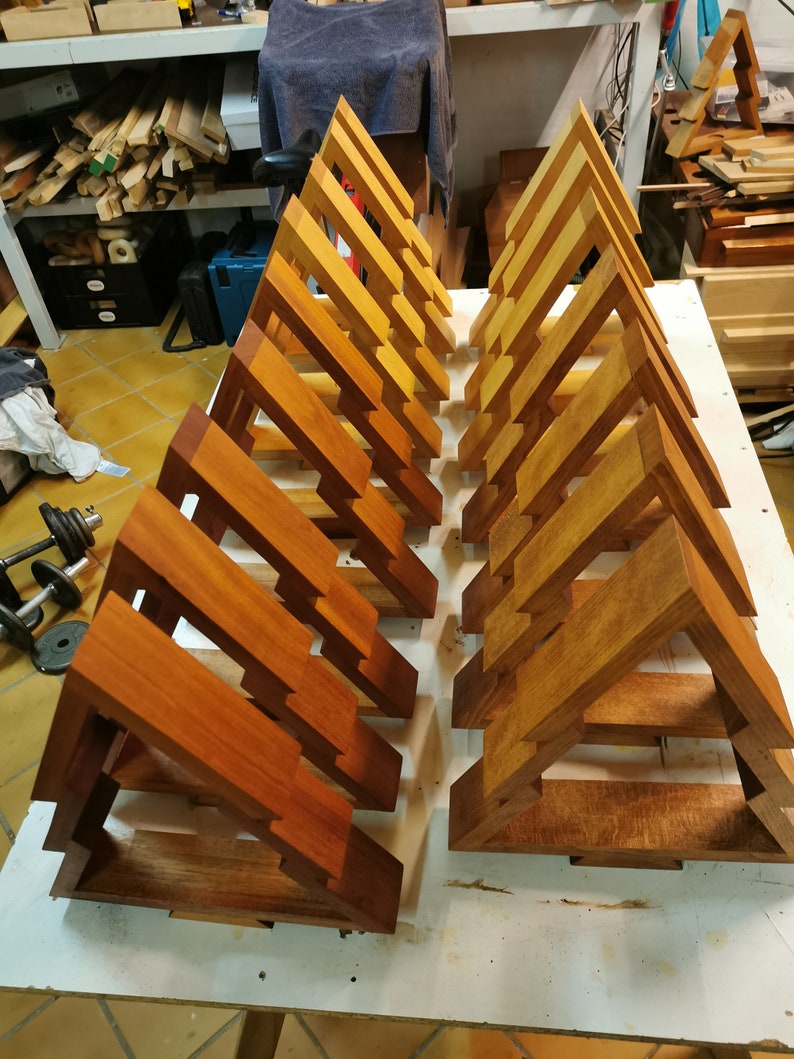May include: A set of 18 unfinished wooden triangular shelves, arranged in two rows of nine. The shelves are made of a light brown wood and have a natural, unpainted finish.