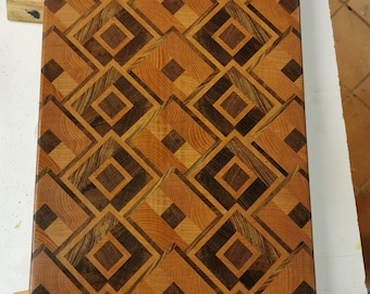 May include: A wooden cutting board with a geometric pattern of dark brown and light brown squares. The board is made of different types of wood, creating a unique and beautiful design.