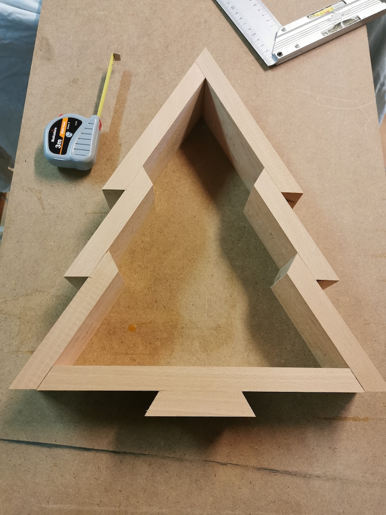 May include: A wooden Christmas tree shaped box, made of light brown wood, with a simple design. The box is assembled and ready to be decorated.