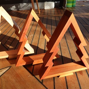 May include: Three wooden Christmas tree ornaments in different shades of brown. The ornaments are made of wood and have a simple, geometric design.