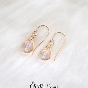 May include: A pair of gold wire wrapped earrings with iridescent white teardrop shaped beads.