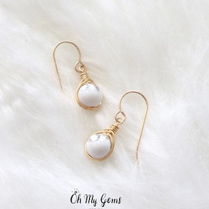 May include: A pair of gold wire wrapped earrings with white howlite stone beads.