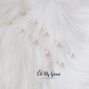 Puede incluir: Elegantes pendientes de plata con perlas colgantes. Cada pendiente presenta una delicada cadena con m&uacute;ltiples perlas, creando un dise&ntilde;o elegante y fluido. Los pendientes se colocan sobre un fondo blanco suave.