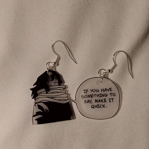 May include: A pair of silver earrings with a black and white anime character on one earring and a speech bubble with the text "If you have something to say, make it quick." on the other earring.
