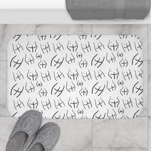 May include: White bath mat with a black and white repeating pattern of stylized human figures.