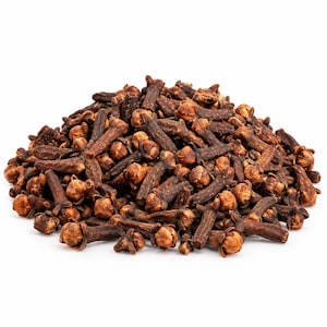 May include: A pile of dried whole cloves, each featuring a dark brown, elongated stem and a lighter tan, rounded flower bud head. The spice pieces are clustered together in a mound against a plain white background, showing varied textures.