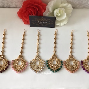 Può includere: Sei pezzi per capelli maang tikka dorati con catene pendenti e dettagli di perle. I maang tikkas presentano una varietà di perline colorate, tra cui viola, rosa, bianco, verde e pesca.