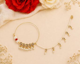 May include: A gold-toned nose ring with a circular design and a delicate chain. The ring features red, green, and white gemstones, along with dangling white pearls. The chain is adorned with small gold accents and pearls, creating an elegant look.
