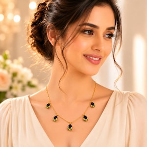 May include: A gold chain necklace featuring five evenly spaced, dark blue, teardrop-shaped pendants. Each pendant is accented with a small, intricate gold floral design at the top, connected by a delicate gold link chain that rests against the collarbone.
