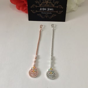 Può includere: Due delicate collane lunghe a catena con un design floreale. La collana a sinistra ha una catena in oro rosa e la collana a destra ha una catena in argento. Entrambe le collane hanno un ciondolo rotondo con un design floreale e pietre color pastello.
