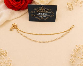 May include: Gold-coloured nose chain with a floral stud and dangling pearls. The chain features two strands: a delicate chain and a strand of small pearls. A black card with gold text reads "A One Jewel, Premium Jewelry."
