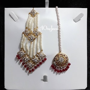 May include: A pair of gold and white bridal headpieces with red beads. The headpieces feature intricate designs with clear stones and pearls.