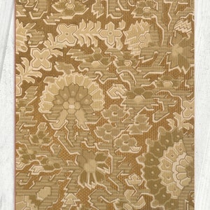 May include: A brown and beige patterned fabric with a repeating floral design. The fabric has a textured surface and a subtle sheen.