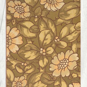 May include: A vintage floral wallpaper pattern with a brown background and beige flowers. The flowers have a light peach center and are surrounded by brown leaves.
