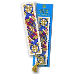 May include: A Celtic Birds bookmark kit featuring two bookmarks with a cross-stitch design. The bookmarks have a blue bird design with gold, red, and green accents. The kit includes a blue package with the text "Celtic Birds Bookmark Kit" and a gold tassel.