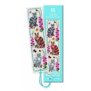May include: Two cross-stitch bookmarks with cat, flower, and butterfly designs. The bookmarks have a blue border and a blue tassel. The packaging reads "CATS BOOKMARK KIT". The cats are grey, brown, and grey-blue.