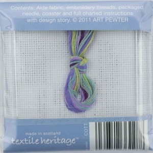 May include: A cross-stitch kit with a white Aida fabric, a bundle of colorful embroidery threads in shades of purple, green, and yellow, and a needle. The package includes instructions and is from Textile Heritage.