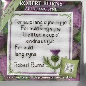 May include: A counted cross-stitch kit featuring the text of Robert Burns' poem "Auld Lang Syne." The design includes a thistle and is set against a purple and green plaid background. The kit is a 250th Anniversary Design.