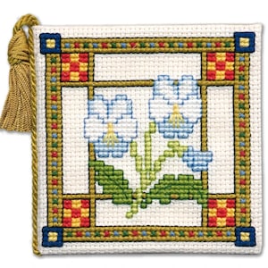 May include: Square cross-stitch design featuring blue flowers with yellow centers and green leaves, framed by a gold border with red, yellow, and blue accents. A gold tassel hangs from the top left corner.
