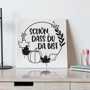 May include: Black and white print with a wreath of leaves and a pumpkin. The text reads "Sch&ouml;n dass du da bist".