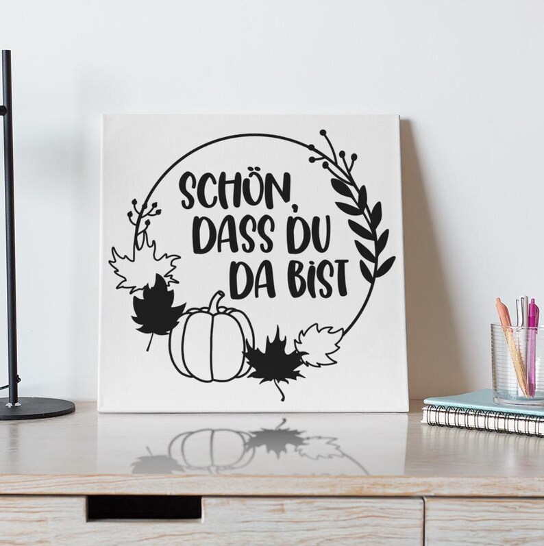 May include: Black and white print with a wreath of leaves and a pumpkin. The text reads "Sch&ouml;n dass du da bist".