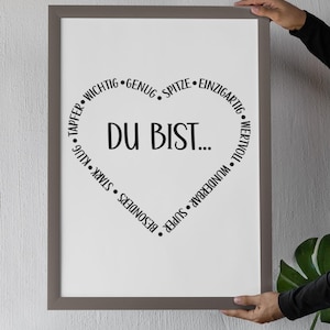 Puede incluir: Una impresi&oacute;n enmarcada con fondo blanco y texto negro. El texto dice "DU BIST..." en forma de coraz&oacute;n con palabras como "wertvoll", "wunderbar", "super", "besonders", "stark", "klug", "tapper", "wichtig", "genug", "spitze" y "einzigartig" rodeando el coraz&oacute;n.