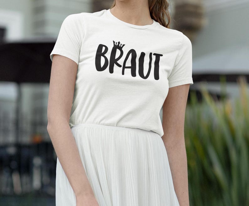 May include: White t-shirt with a black crown and the word "BRAUT" printed on the front.