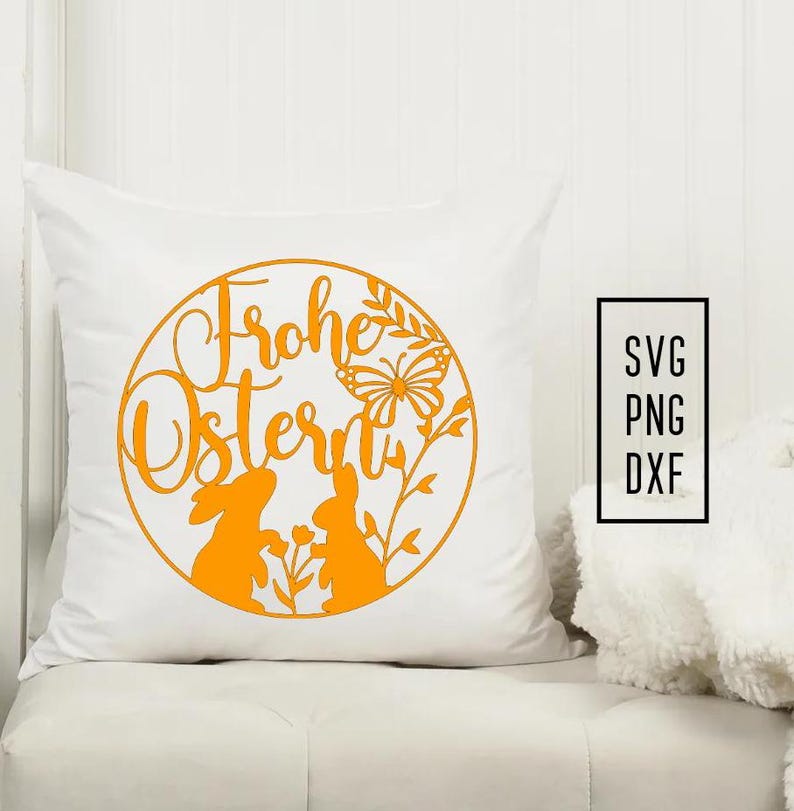 Puede incluir: Almohada blanca con un dise&ntilde;o redondo naranja con el texto "Frohe Ostern" con dos conejos y una mariposa. Se enumeran los formatos de archivo SVG, PNG y DXF.