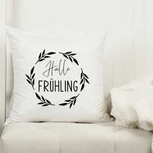 May include: White throw pillow with black text and a wreath of leaves that says "Hallo Fr&uuml;hling".