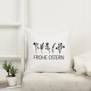 Peut inclure: Un oreiller blanc avec un motif floral noir et le texte "Frohe Ostern" (Joyeuses P&acirc;ques en allemand).