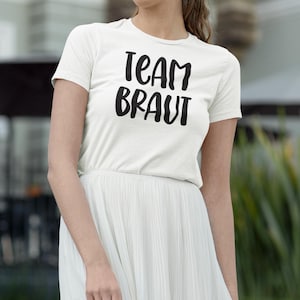 May include: White t-shirt with black text that reads "Team Braut".