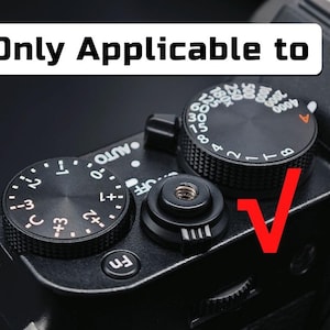 May include: A black camera top plate featuring a shutter button, a function button, and two circular control dials with white markings. One dial displays exposure compensation values, while the other shows shutter speeds. Text reads Only Applicable to.